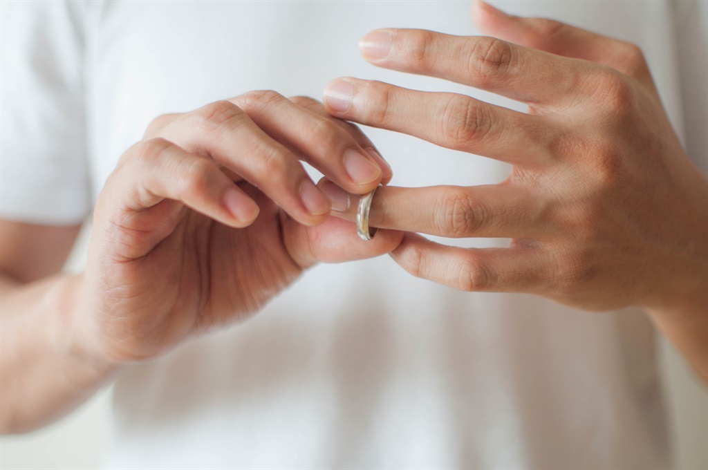 Man's hands removing his wedding ring a concept of relationship difficulties