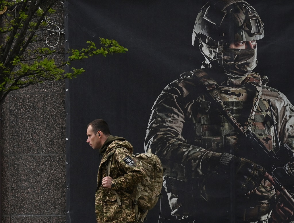 A Ukrainian serviceman walks past a recruiting poster in Kyiv on 23 April 2024, amid the Russian invasion of Ukraine. (Sergei SUPINSKY / AFP)