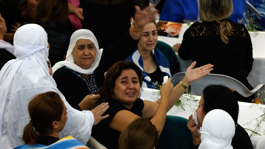 Druze women mourn near the coffins of loved ones a