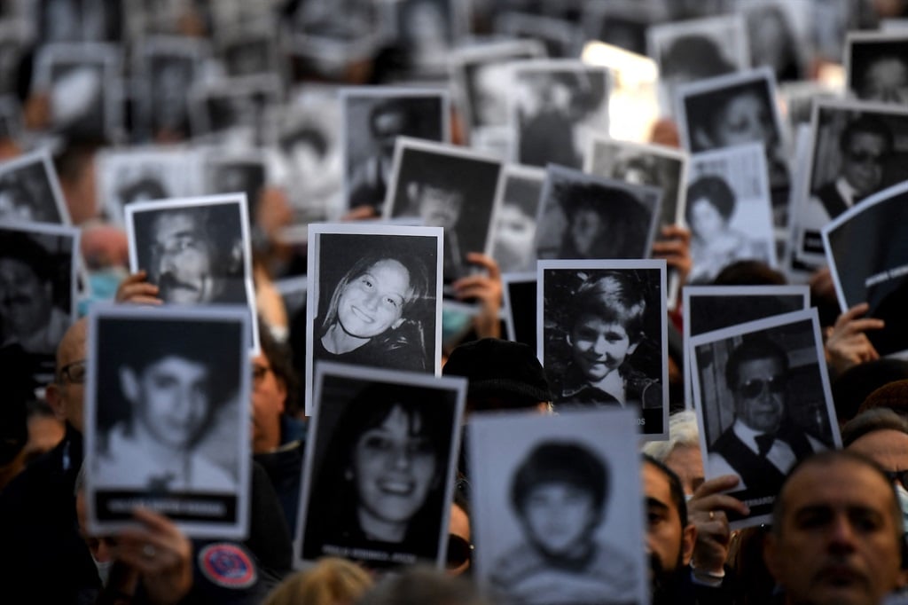 Relatives of victims of a bomb attack on the Jewish community centre of the Mutual Israelite Association of Argentina (AMIA) that killed 85 people and injured 300, hold photos during its 28th anniversary, in Buenos Aires, Argentina, in July 2022. (Luis ROBAYO / AFP)
