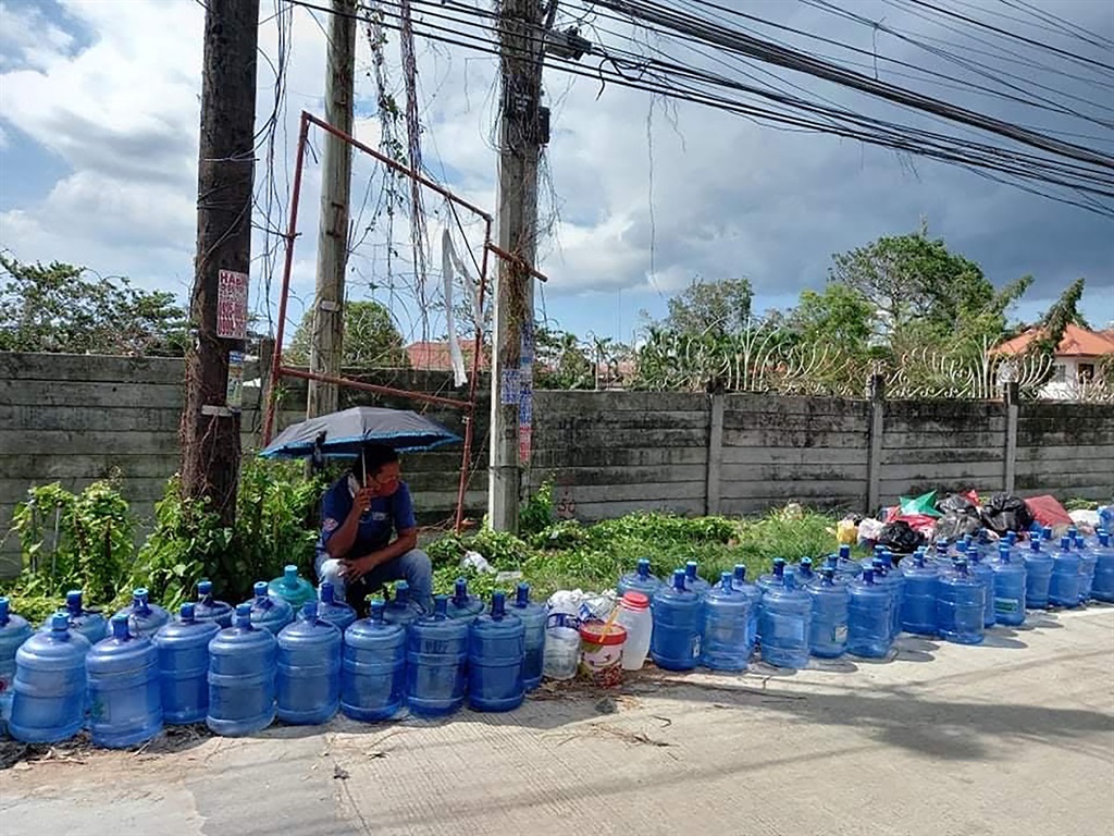 Residents with their water plastic containers queue up to fetch water along a road in Tagbilaran City, Bohol province on December 20, 2021, days after super Typhoon Rai hit the province.