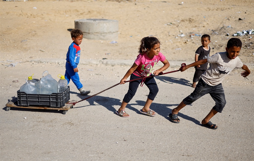 Palestinian children pull water containers as peop