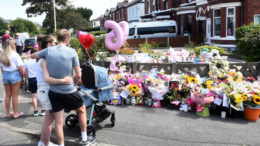 Residents look at floral tributes for the victims of a deadly knife attack in Southport, northwest England. (Peter Powell/AFP)