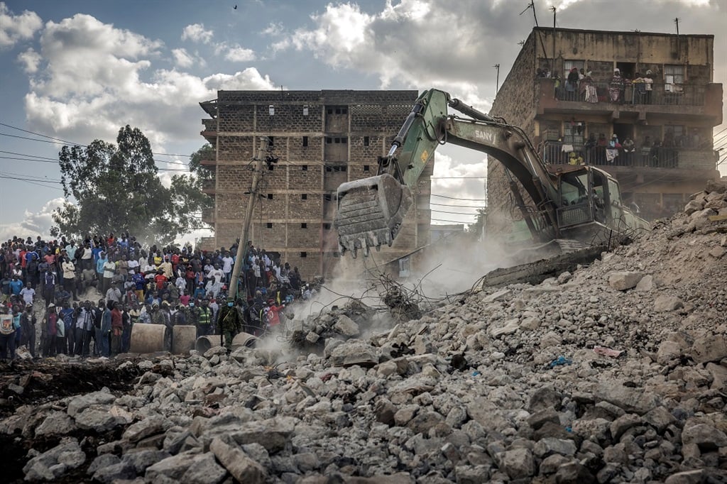 Bystanders follow rescue operations in front of a collapsed building that was under demolition in the Mathare informal settlement of Nairobi, on 14 May. (Luis Tato/AFP)