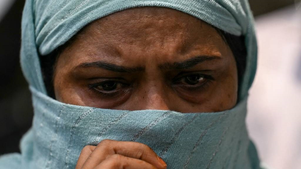 A relative of an infant victim cries as she waits 