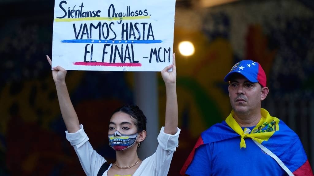 A Venezuelan woman holds a sign that reads in Span