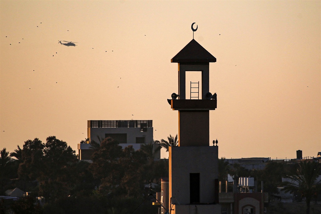 The minaret of a mosque stands in al-Zawayda as an Israeli military helicopter flies over the central Gaza Strip on August 8, 2024, amid the ongoing conflict between Israel and the militant group Hamas. (Eyad Baba/AFP)