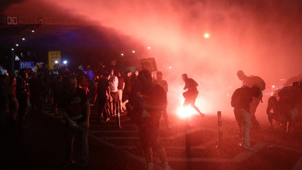 Israeli left-wing protesters are sprayed with wate