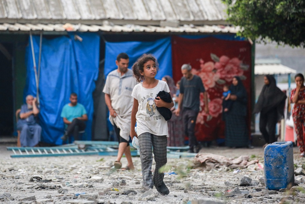 A Palestinian girl walks above debris at a UN-scho