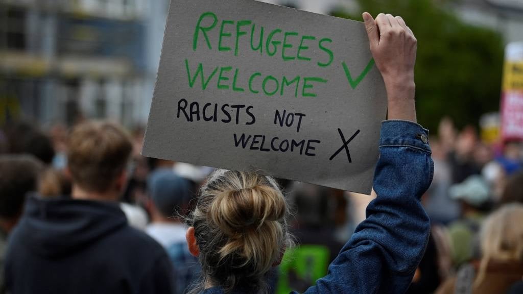 A protester holds a placard during a counter demonstration against an anti-immigration protest called by far-right activists, outside the Asylum Welcome immigration support service offices in Oxford, western England. (Justin Tallis/AFP)