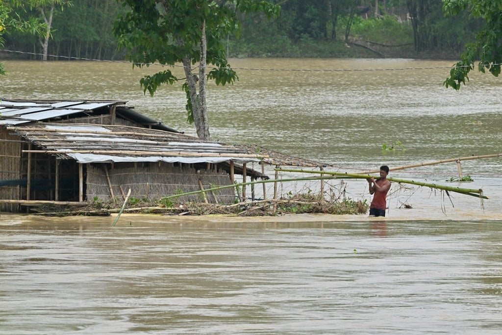 A villager carries bamboo through a flood-affected area after heavy rains in Nagaon district of India's Assam state earlier this month. (Biju Boro/ AFP)