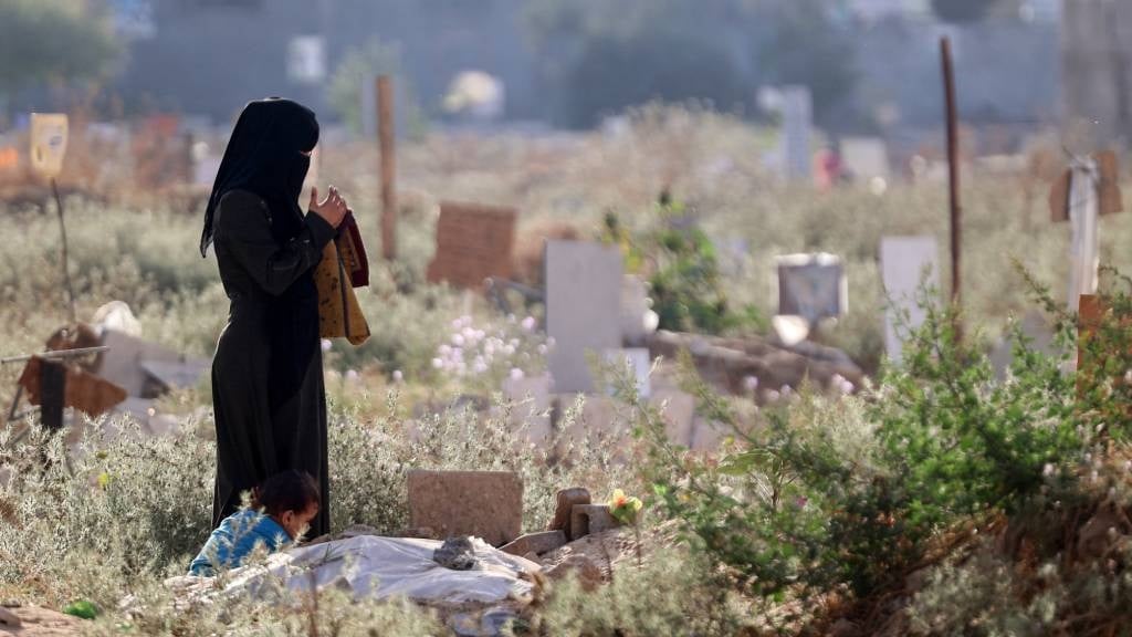 A Palestinian woman prays near the grave of a rela