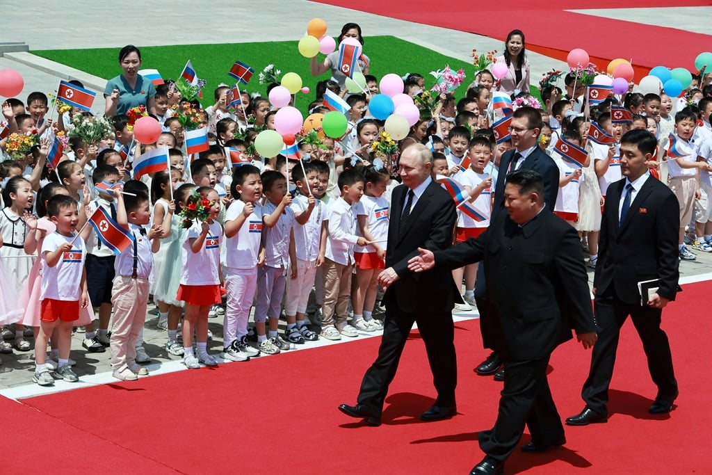 North Korea's leader Kim Jong Un (centre-R) and Russian President Vladimir Putin (L) walk past children during a welcoming ceremony at Kim Il Sung Square in Pyongyang on 19 June 2024. (Vladimir Smirnov/Pool/AFP)