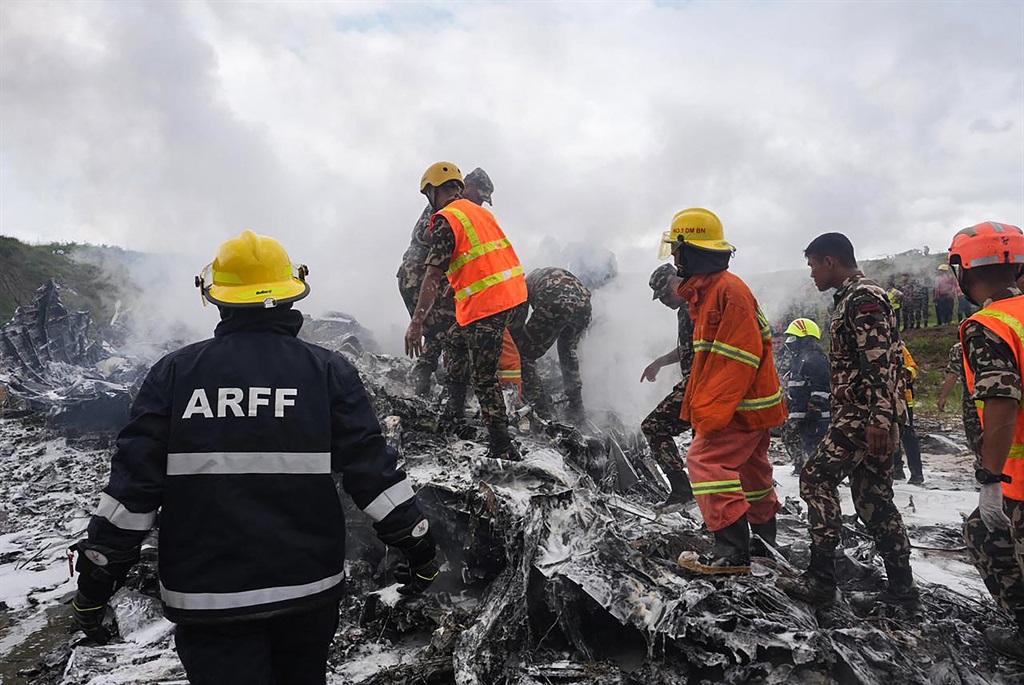 Rescuers and army personnel stand at the site afte