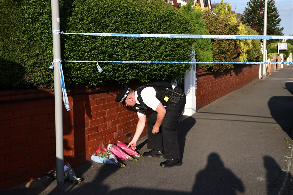  A police officer lays floral tributes brought by 