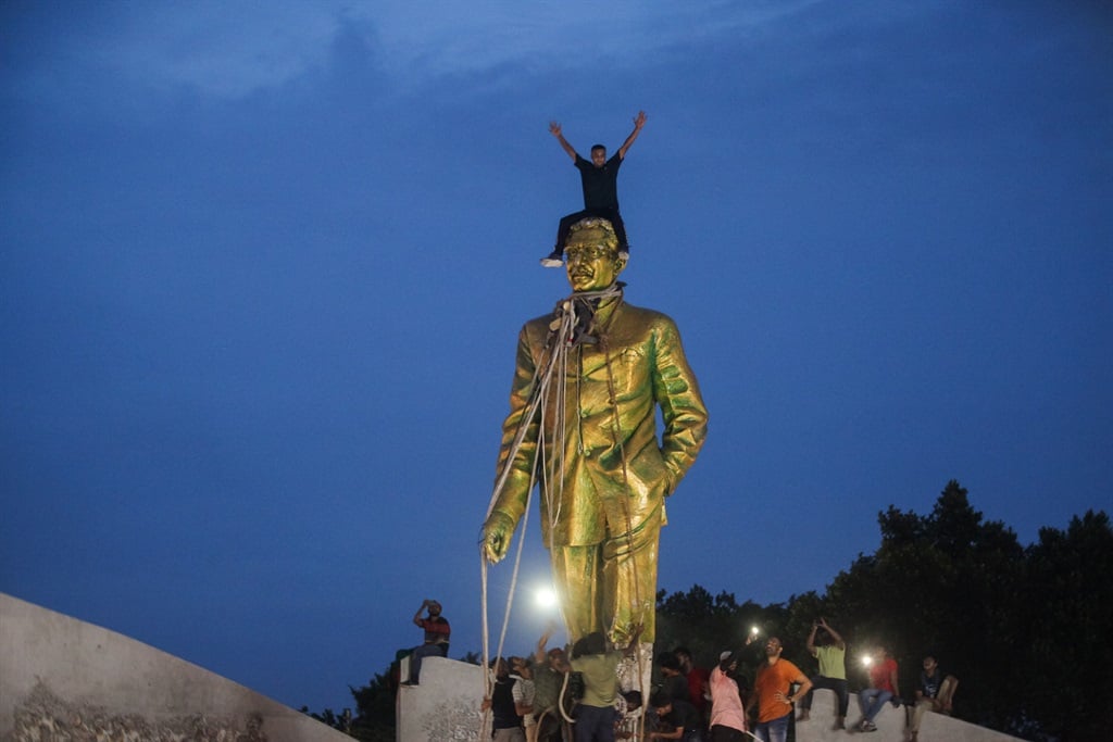 Protesters on top of a statue of Sheikh Mujibur Rahman, Bangladesh's founding father and parent of ousted Prime Minister Sheikh Hasina, in Dhaka on 5 August 2024. (Abu SUFIAN JEWEL / AFP)