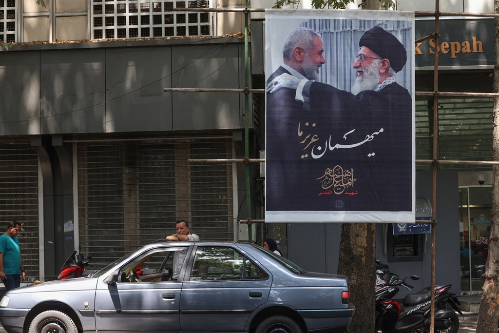 People walk past a poster of Iranian supreme leader Ayatollah Ali Khamenei (R) and slain Palestinian Hamas leader Ismail Haniyeh in Iran's capital, Tehran, on 10 August 2024, amid regional tensions during the ongoing war between Israel and Hamas in the Gaza Strip. (Atta Kenare/AFP)