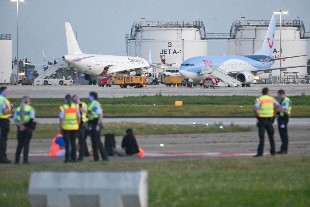 Climate activists on a tarmac at Stuttgart Airport. (Marius Bulling/picture alliance).