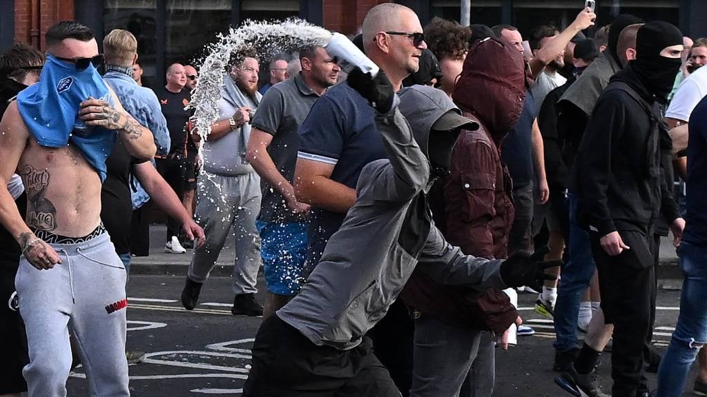 A masked protester hurls a can toward police as cl