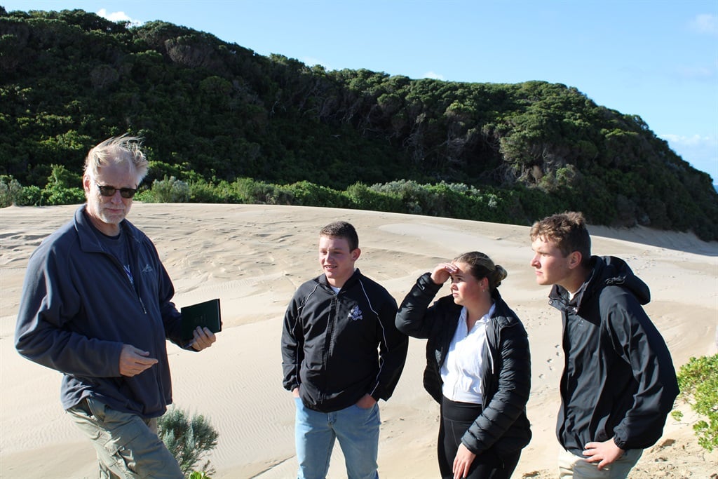 Image of four people on sand dune.