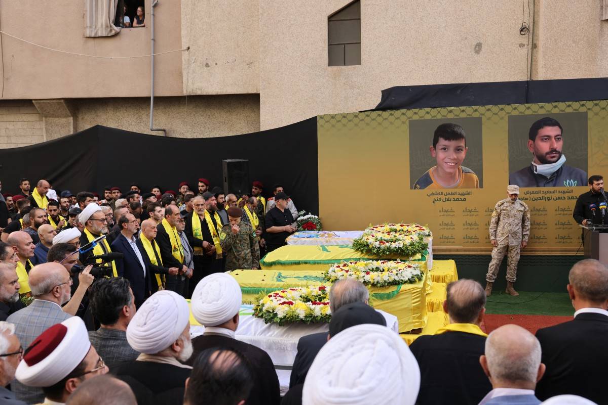 Mourners, clerics and Hezbollah members stand by the coffins of people who died when paging radios exploded in Lebanon.  