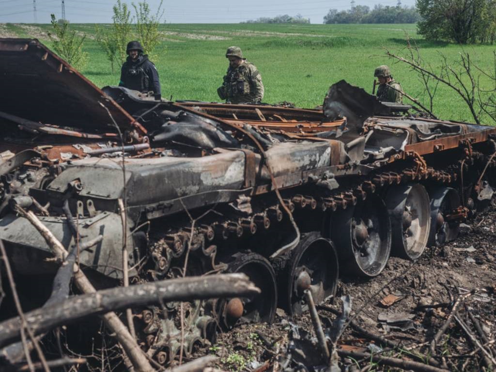 Ukrainian soldiers stand next to a destroyed Russian tank on the outskirts of Kharkiv, Ukraine.