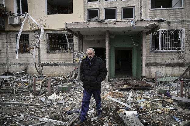 A man walks away from the entrance of a destroyed apartment block following shelling in the northwestern Obolon district of Kyiv.