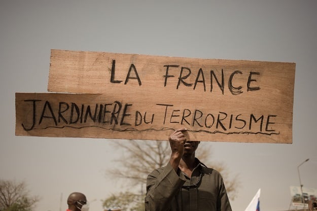 A protester holds a placard reading "France, gardener of terrorism" to celebrate Frances's announcement to withdraw French troops from Mali.
