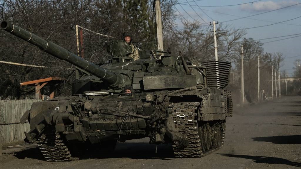 Ukrainian servicemen drive a tank in the village o