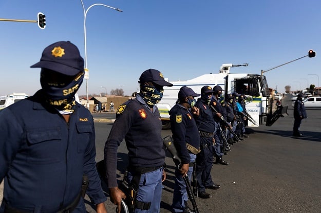 SAPS officers form a line in the road during a protest. 