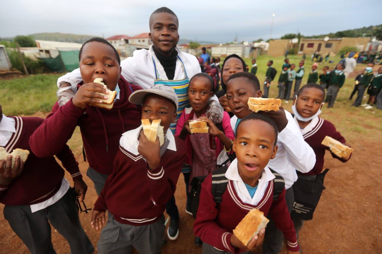 Jacob Madisha (white jacket) and his friends giving food to about 200 kids (insets) at Brazzaville Sports Ground in Atteridgeville, Tshwane, three days a week before they go to school.                                                  Photos by Raymond Morare