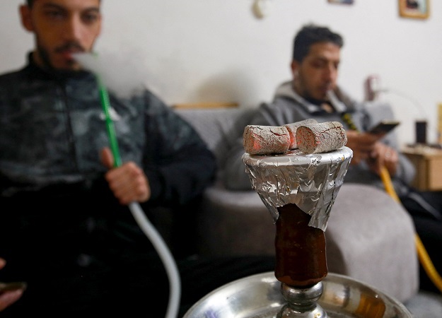 Jordanian men smoke hookah water-pipes inside a ho