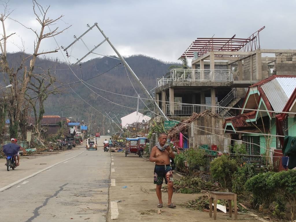 A resident walks past a damaged electric pylon in Del Carmen town in Surigao del Norte province, days after Super Typhoon Rai devastated the province.