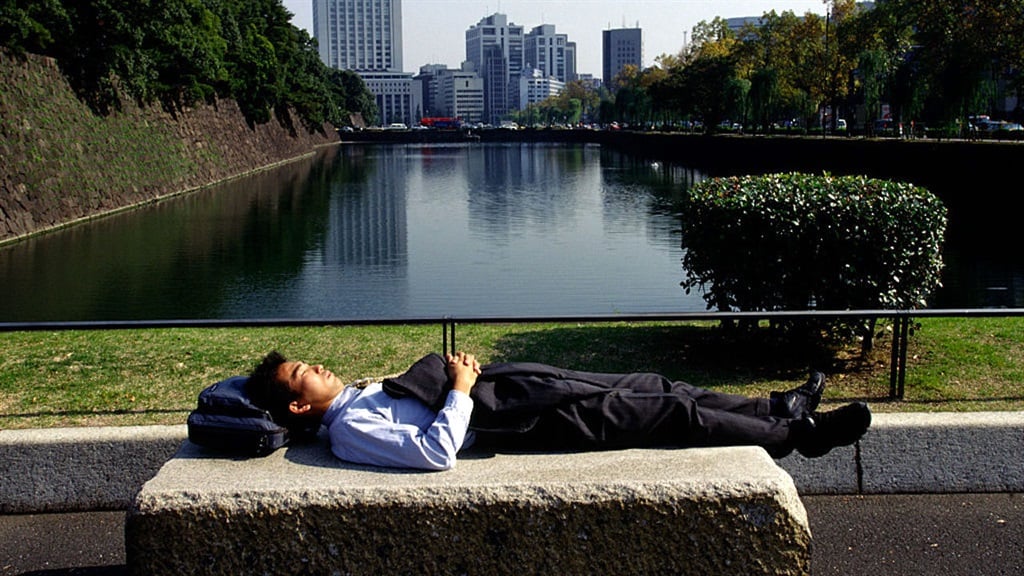 A salaryman takes a nap in the public grounds of t