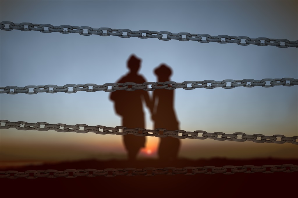 Chain fence with the silhouette of a refugee couple. 
