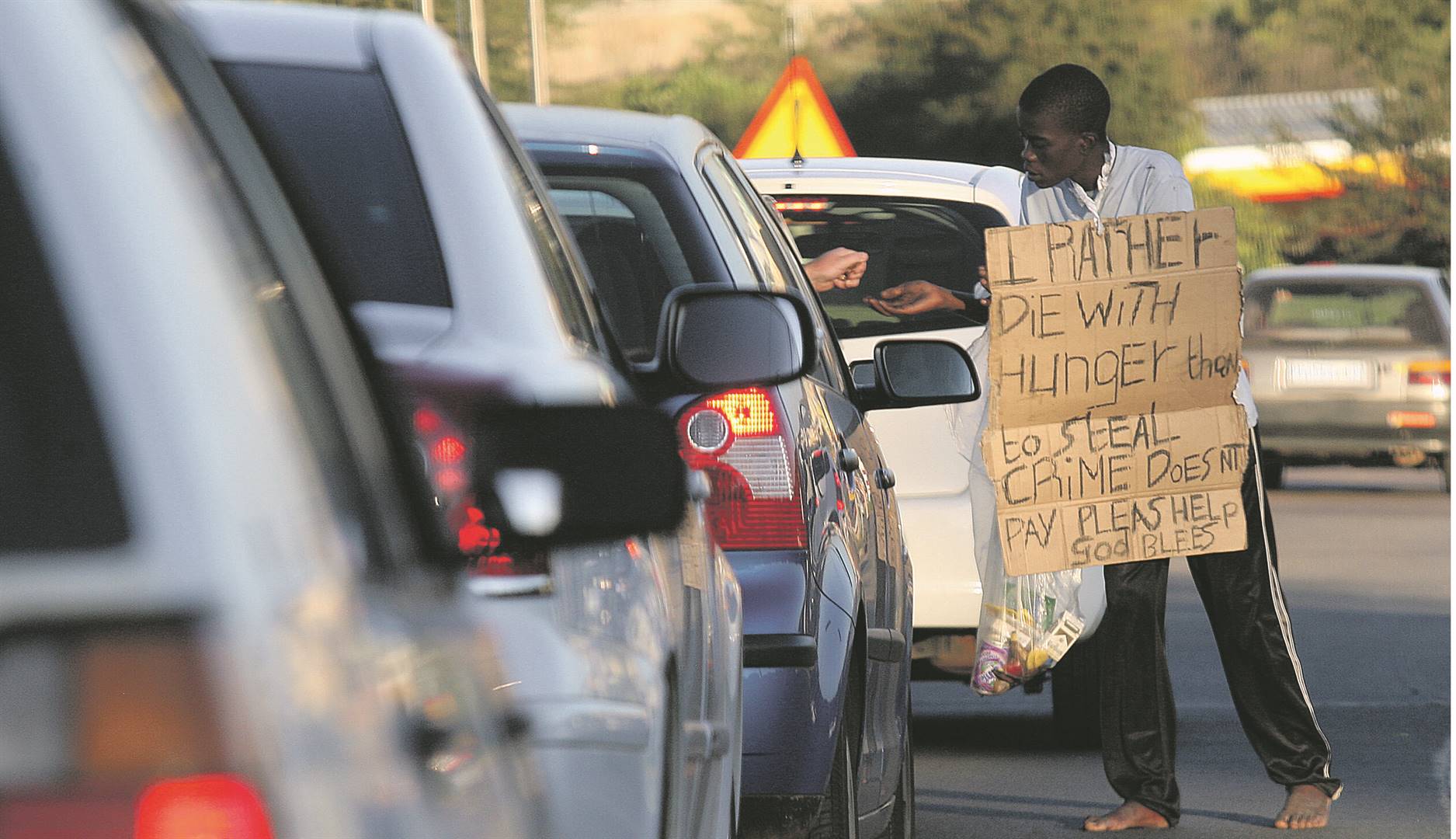 An unemployed man receives money from a motorist on Atterbury Road in Menlo Park, Pretoria, as SA’s unemployment rate continues to skyrocket Photo: Khaya Ngwenya