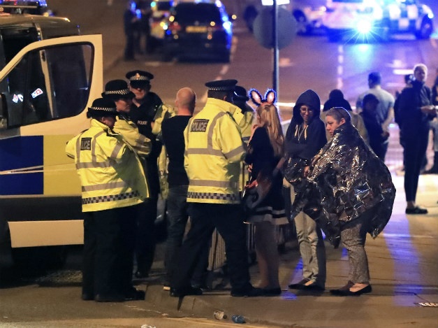 Emergency services personnel speak to people outside Manchester Arena after reports of an explosion at the venue during an Ariana Grande concert in Manchester, England (Peter Byrne/AP)