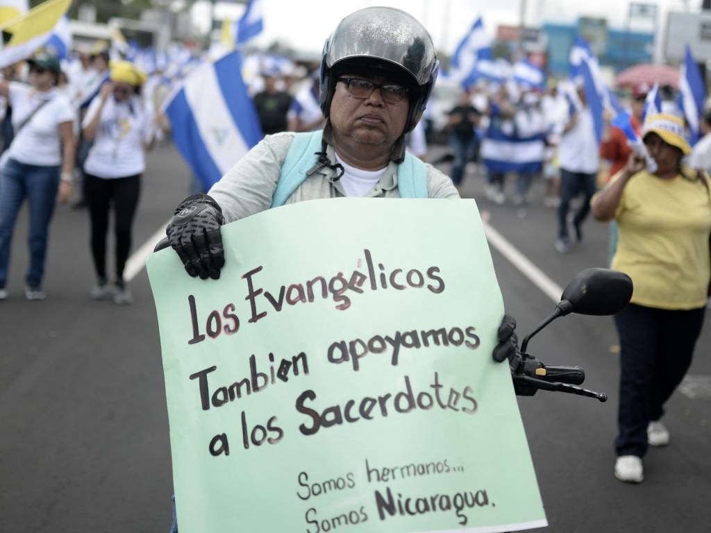 An anti-government demonstrator holds a sign reading 'Protestants also support Priests. We are brothers. We are Nicaragua' during a pilgrimage in Managua.