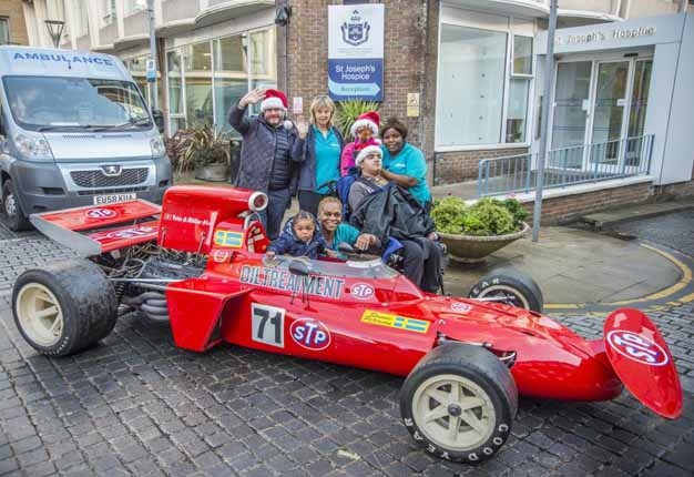 <B> FAST SANTA:</B> Chris Routledge from Coys (left) delivers presents in Niki Lauda's first F1 car to Richard House youngsters Arun (18), Roman (1) and the nurses of Richard House. <I>Image: Newspress / Dick Barnett </i>