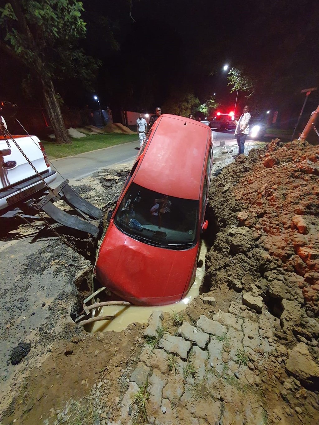 Red car crashed into deep hole left behind