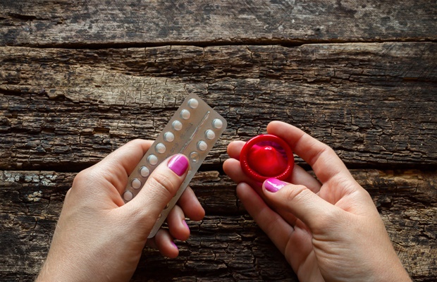 woman holding the pill and condom