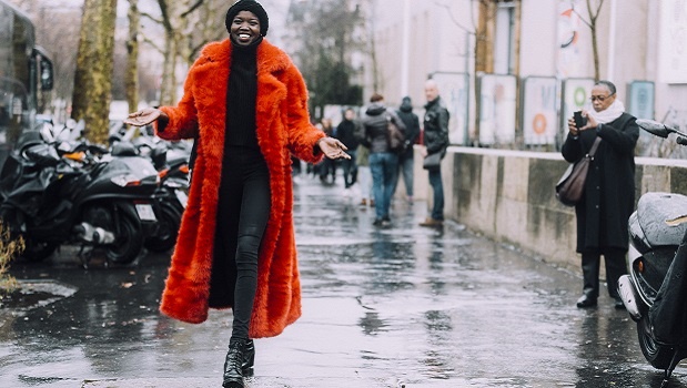 Woman wearing bright coat walks down the street. 