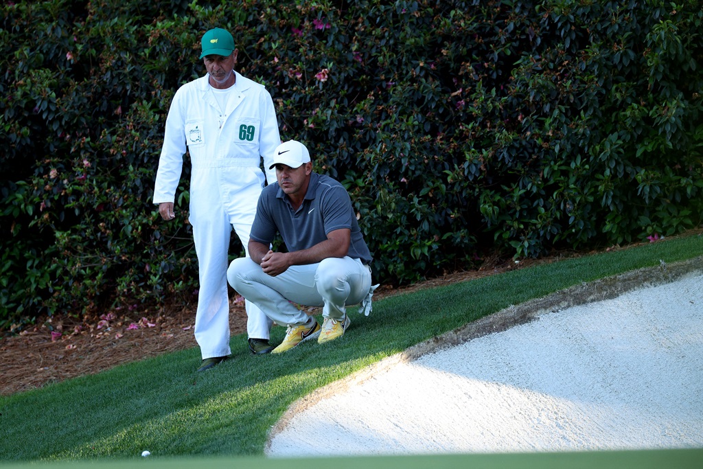 Brooks Koepka of the United States talks with his caddie Ricky Elliott on the 13th green during the final round of the 2023 Masters Tournament at Augusta National Golf Club
