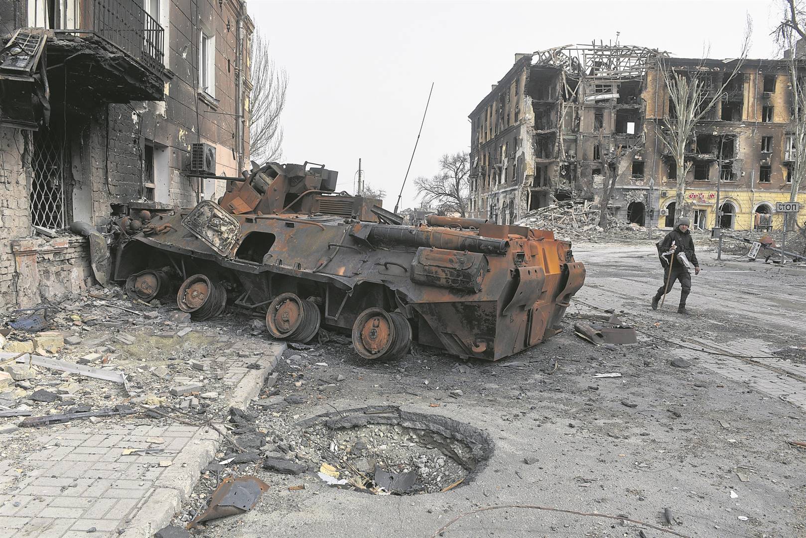 A man walks past a burnt armoured personnel carrier near buildings destroyed in the course of Ukraine-Russia conflict in the southern port city of Mariupol, Ukraine yesterday. PHOTOS: Reuters