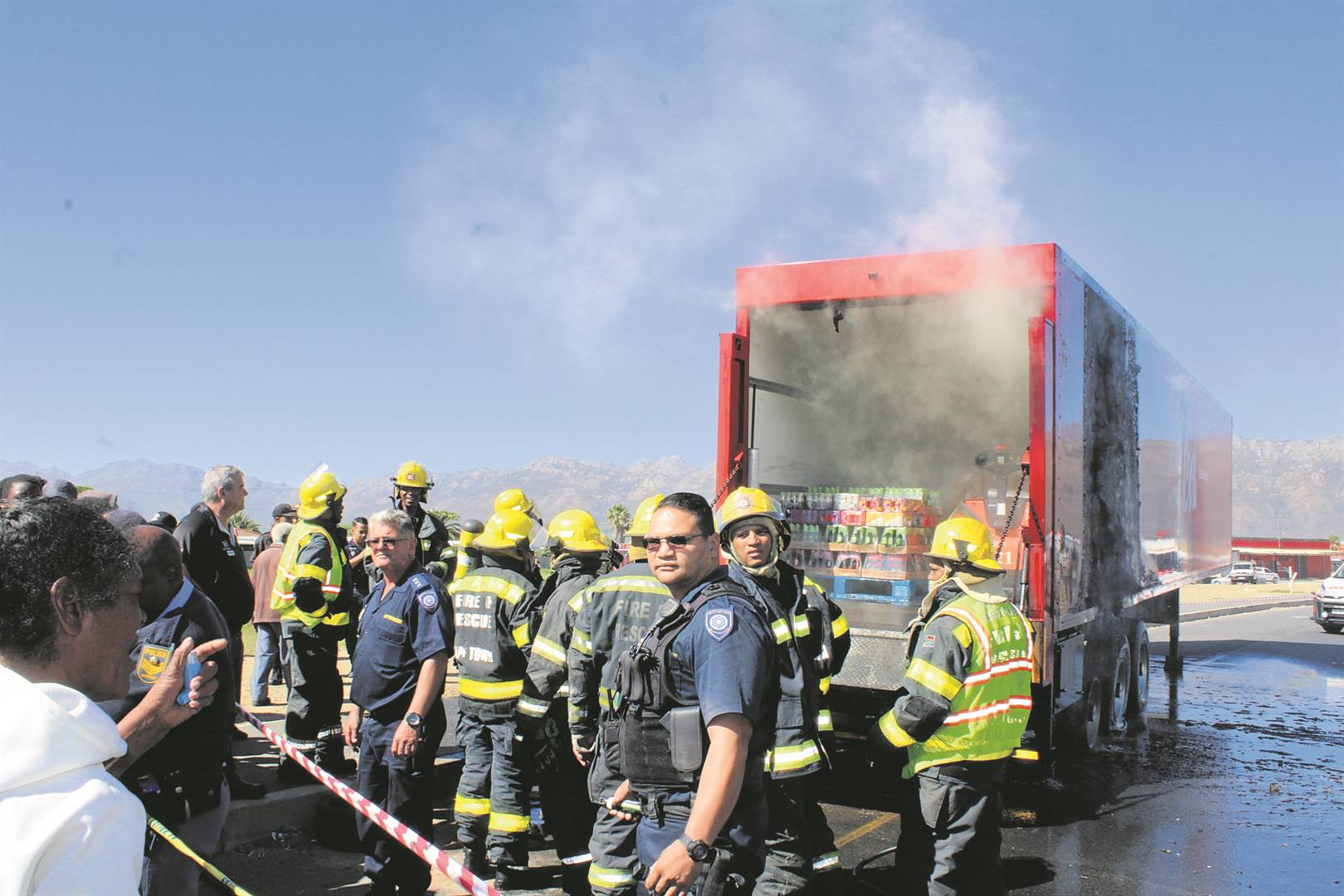 Firefighters on the scene hosing down the Coca-Cola truck and trailer that erupted in flames in Broadway Boulevard, Strand, on Tuesday (18 April).Photo: Yaseen Gaffar 