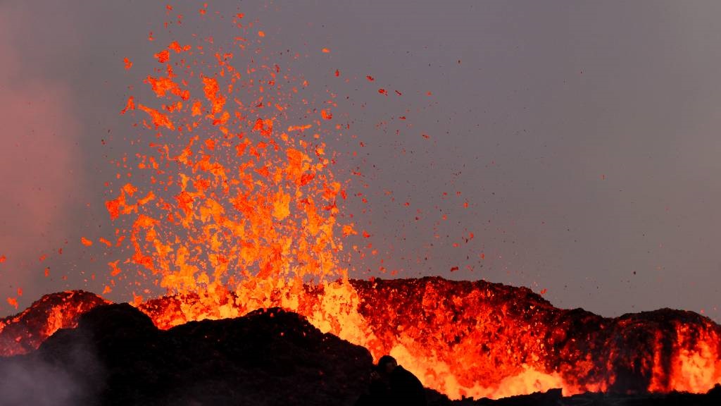 People watch flowing lava during an volcanic erupt