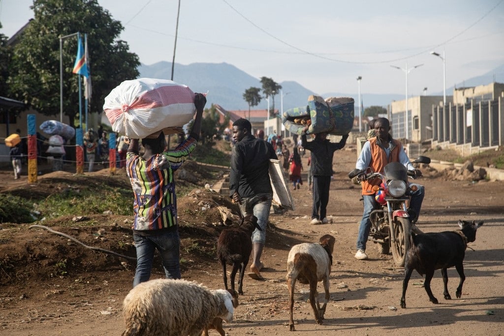 People carrying bundled belongings and livestock