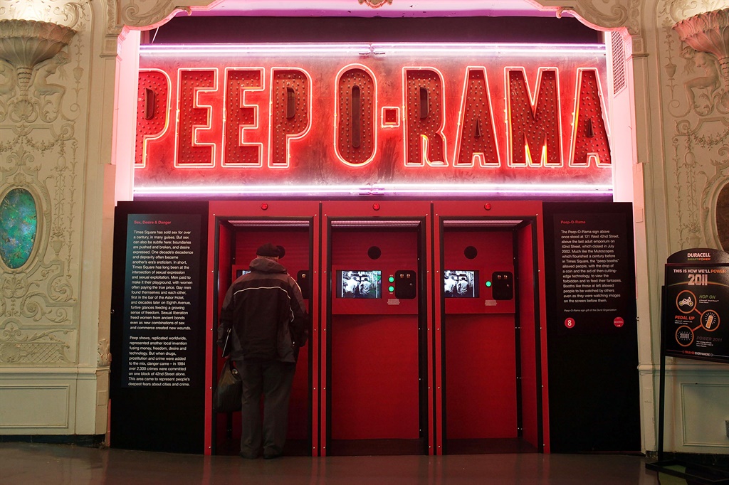 A man stands under one of the most famous peep show signs of the past, Peep -O-Rama, which has been refurbished and moved to the visitor?s center run by the Times Square Alliance
