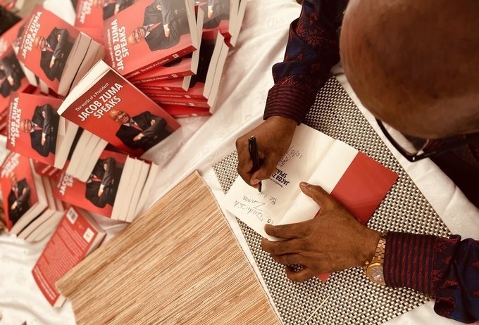 Former president Jacob Zuma signs a copy of his book.