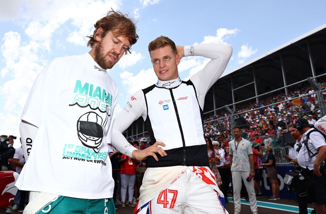 Sebastian Vettel of Germany and Aston Martin F1 Team and Mick Schumacher of Germany and Haas F1 talk on the grid during the F1 Grand Prix of Miami at the Miami International Autodrome on May 08, 2022 in Miami, Florida. 